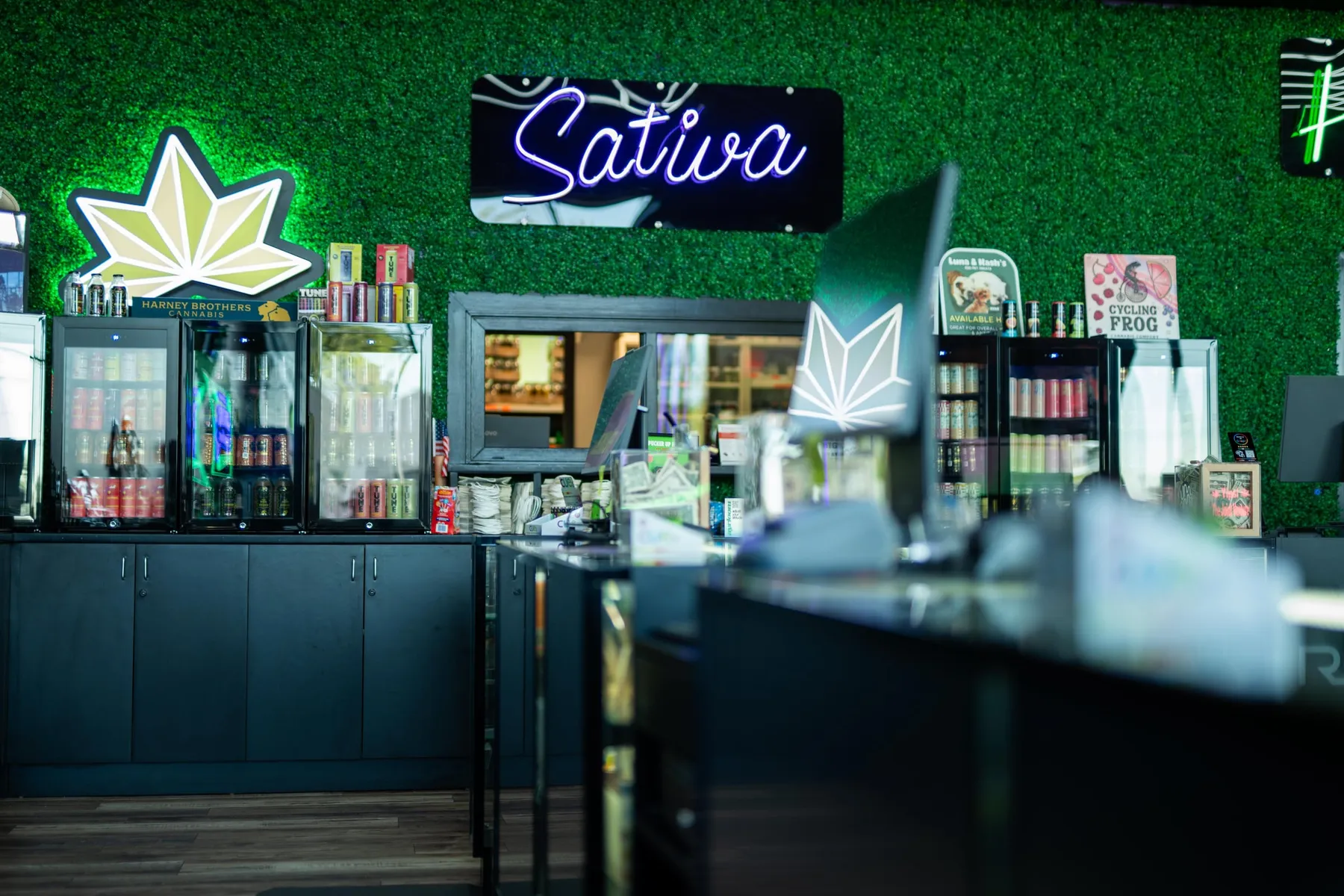 The service counter under the Sativa neon at The Joint Venture in Medford, where budtenders work with customers.