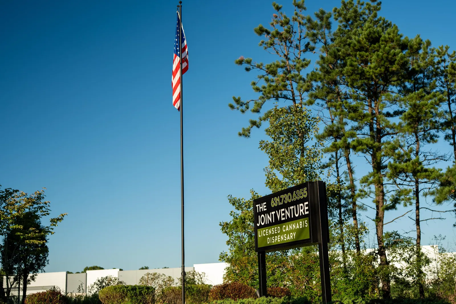 The Joint Venture's roadside sign with its phone number, beside the flagpole on Munsell Road.